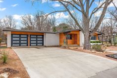 a house with two garages and trees in the background