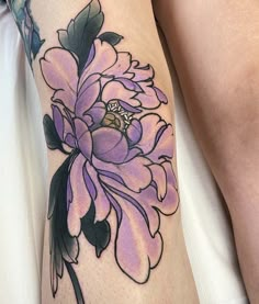 a close up of a person's leg with a flower tattoo on the thigh