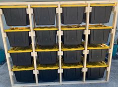 several plastic bins are stacked on top of each other in a storage rack with yellow shelves