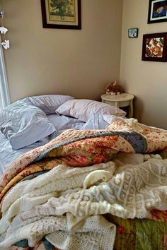 an unmade bed with blankets and pillows on top of it in a bedroom next to a window