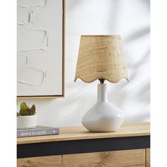 a white table lamp sitting on top of a wooden dresser