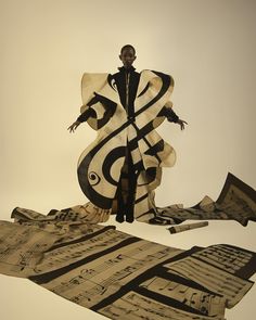 a man standing on top of a pile of musical paper cut out into the shape of music notes