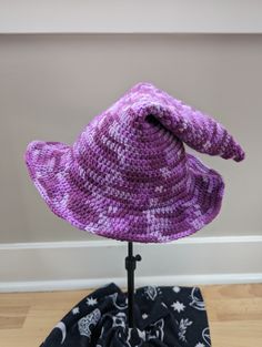 A handmade crochet witch hat made with purple mottled acrylic yarn. Made to be slouchy and comfy, with a moldable wire brim. Cozy muted purples ranging from lavender to deep eggplant.  Hat has a 11" diameter straight across the brim at the widest point. The inside circumference is roughly 20-22" - it can stretch a bit. Pattern: TheEntangledFae - https://www.etsy.com/shop/TheEntangledFae Hand Knitted Purple Hat One Size, Hand Knitted Purple Hat, Hand Knitted Purple Yarn Hats, Hand Knitted One Size Purple Hats, Hand-knitted One Size Purple Hat, Adjustable Hand Knitted Purple Crochet Hat, Adjustable Hand-knitted Purple Crochet Hat, Adjustable Purple Crochet Hat, Adjustable Purple Hand Knitted Crochet Hat