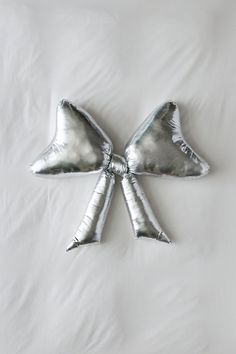 two silver bow shaped pillows laying on top of a bed