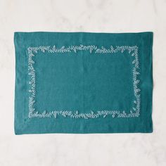 a green place mat with white stitching on it, sitting on a marble surface