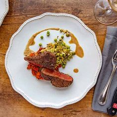 a white plate topped with meat and veggies on top of a wooden table