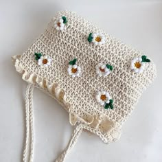 a crocheted bag with flowers on it sitting on top of a white table