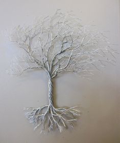 a metal tree with white branches hanging on a wall