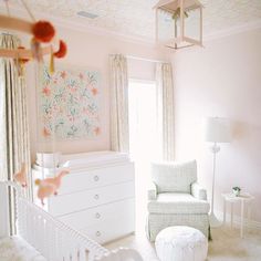 a baby's room with pink walls and white furniture