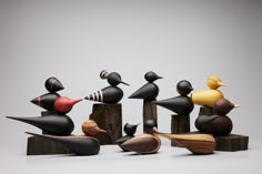 an assortment of wooden birds sitting on top of each other in front of a gray background