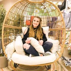 a woman sitting in a hanging chair with pillows