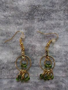 Green Dangle Hoop Earrings With Beaded Fringey Bottoms MATERIALS: -GREEN GLASS SEED BEADS -RUBBER EARRING BACKINGS -GOLD PLATED ALLOY METAL JUMP RINGS, EARRING WIRES AND HOOP EARRING FINDINGS Introducing our chic and trendy Green Dangle Hoop Earrings. These eye-catching earrings are designed to add a touch of elegance to any outfit. Made with high-quality materials, the hoops feature a stunning green color that is sure to complement any skin tone. The beaded fringey bottoms add a playful and sty Green Beaded Dangle Hoop Earrings, Green Hoop Earrings With Dangling Beads, Green Hoop Beaded Earrings With Dangling Beads, Green Beaded Earrings With Round Metal Beads, Green Metal Round Bead Earrings, Green Metal Beaded Earrings With Round Beads, Green Beaded Metal Earrings, Green Metal Beaded Earrings For Party, Green Metal Beaded Drop Earrings