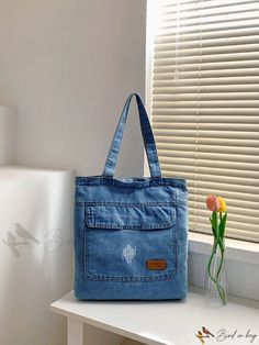 a blue bag sitting on top of a white table next to a vase with flowers