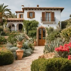 a white house surrounded by greenery and potted plants