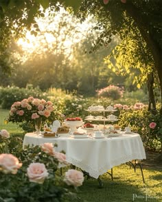 a table covered with food and flowers in the middle of a garden at sunset or sunrise