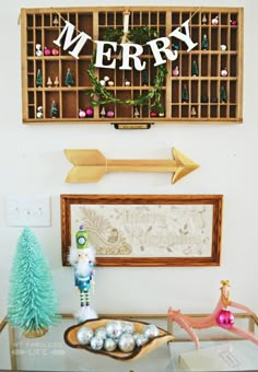 a table with christmas decorations on it and a merry sign hanging above the top shelf