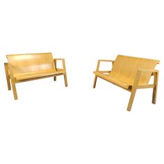 two wooden chairs sitting next to each other on a white surface with no one in it