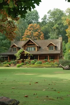 a large log house in the middle of a lush green field with lots of trees