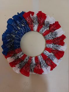 an american flag ruffle wreath on a white table with red, white and blue colors