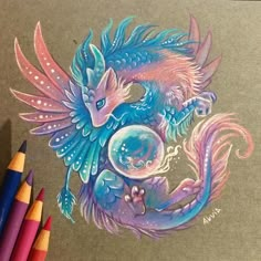 a drawing of a blue dragon with bubbles on it's body and wings, sitting next to colored crayons