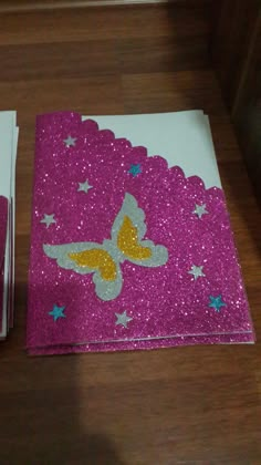 two napkins with glitter butterflies on them sitting on a wooden table next to each other