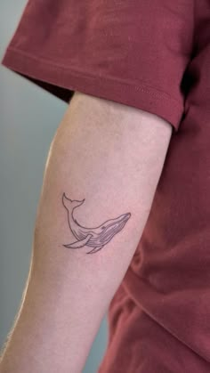 a person with a tattoo on their arm that has a whale tail in the middle