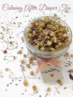 a glass jar filled with dried flowers on top of a white table next to a tag that says calming after dinner tea