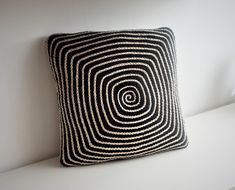 a black and white pillow sitting on top of a white shelf