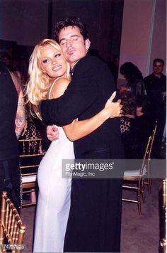 a man and woman hugging each other in front of some chairs at a formal event