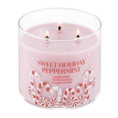 a pink candle with candy canes on it