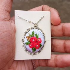 a hand holding a white card with red flowers on it and a chain attached to it