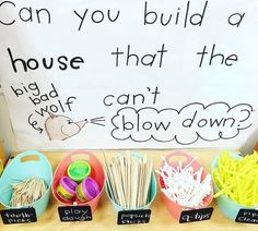 a table with bowls, cups and spoons in front of a sign that says can you build a house that the big boy can't show down?