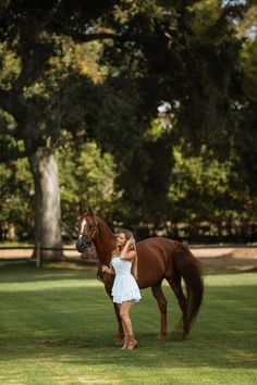 a woman standing next to a brown horse