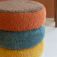 four different colored cushions stacked on top of each other in the shape of a round