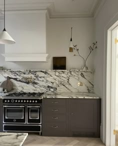 a kitchen with marble counter tops and an oven in the center, along with two pendant lights hanging from the ceiling