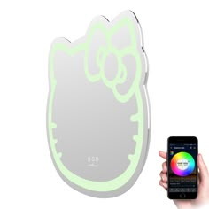 a person holding a cell phone in front of a hello kitty light up wall mirror