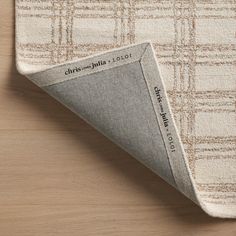 a beige and white rug on top of a wooden floor with an area rug underneath it