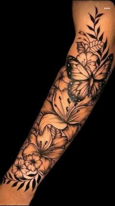 a black and white tattoo with flowers on the left arm, in front of a dark background