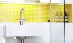 a white sink sitting under a bathroom mirror next to a tiled wall with yellow tiles on it