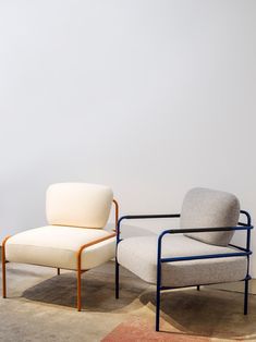 two chairs sitting next to each other on top of a carpeted floor in front of a white wall