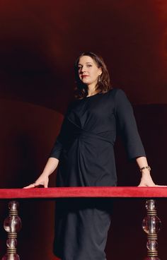 a woman is standing on a red carpet with her hands in her pockets and arms behind her back