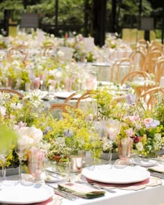 a table set up with plates and vases filled with flowers