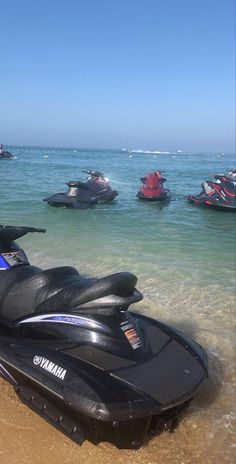 several jet skis are parked on the beach in front of some water skiers