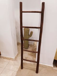 a wooden ladder leaning against the wall next to a potted cactus in a corner