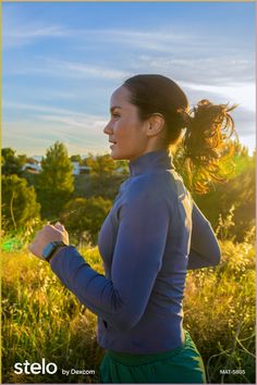 a woman is running in the grass with her hair blowing in the wind and looking off into the distance