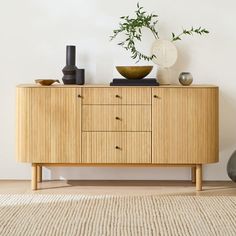 a wooden cabinet with two vases and a bowl on top