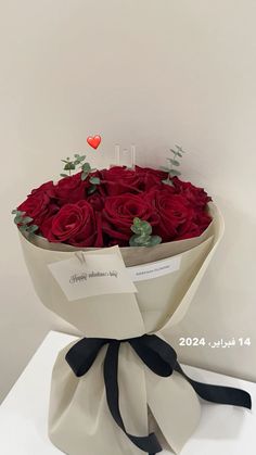 a bouquet of red roses wrapped in white paper