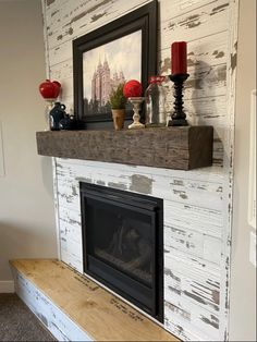 a white fireplace with some red candles and pictures on it's mantels