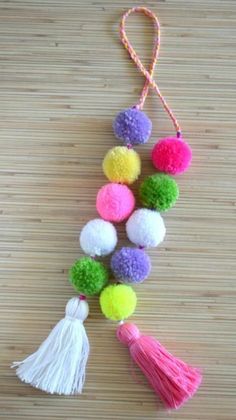 the pom - pom keychain is decorated with multicolored balls and tassels