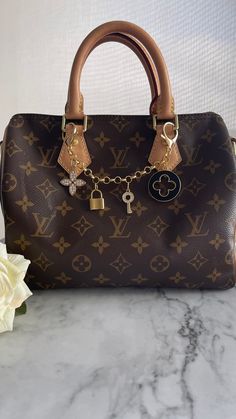 a brown louis vuitton handbag sitting on top of a marble counter next to a white rose